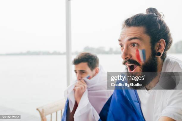 excité fan de football français regarder un match avec un ami à l’appui de la russie - tenue de football photos et images de collection