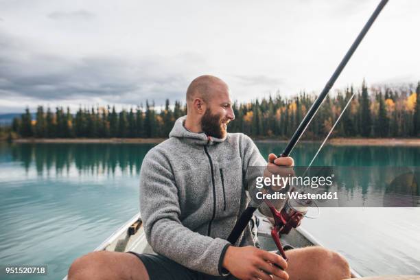 canada, british columbia, man fishing in canoe on boya lake - fishing rod stock-fotos und bilder