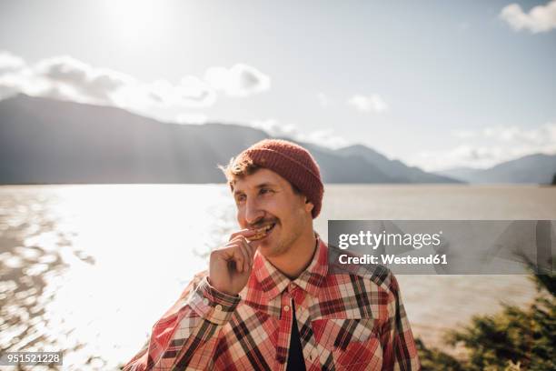 canada, british columbia, portrait of smiling man eating a cookie - pet food stockfoto's en -beelden
