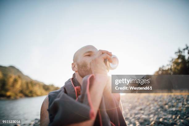 canada, british columbia, chilliwack, man drinking from can at fraser river - blechdose stock-fotos und bilder