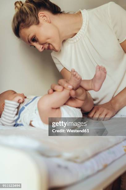 mother smiling at newborn baby on changing table - midwife stock pictures, royalty-free photos & images
