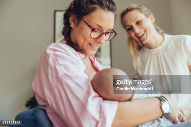 midwife supporting a breastfeeding mother with her newborn baby - mid wife stock pictures, royalty-free photos & images