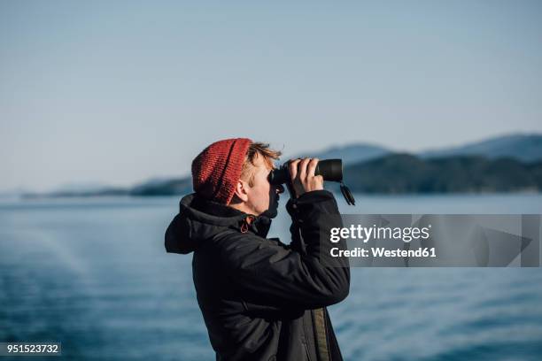 canada, british columbia, man looking through binoculars at the coast - fernglas stock-fotos und bilder