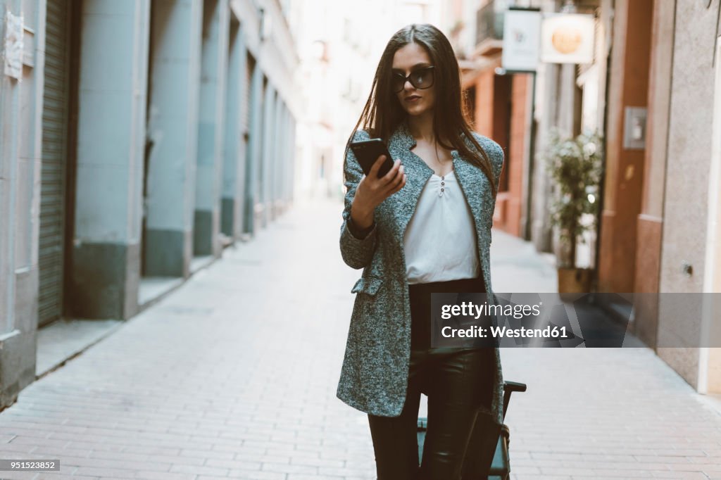 Young businesswoman in the city checking cell phone