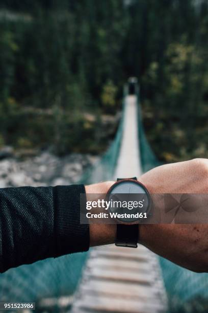 man's hand with watch in front of swinging bridge - checking the time stock pictures, royalty-free photos & images