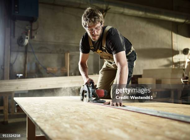 carpenter sawing wood with handsaw - craftsman stock-fotos und bilder