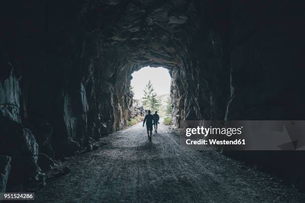 canada, british columbia, kelowna, myra canyon, hikers on kettle valley rail trail crossing a tunnel - thompson okanagan region british columbia stock pictures, royalty-free photos & images