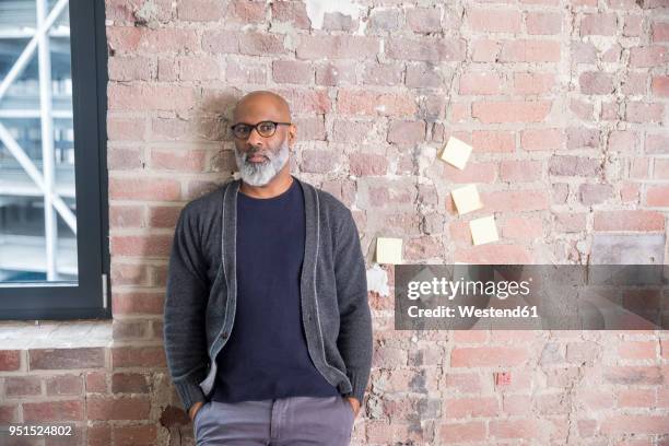 portrait of freelancer leaning against wall in a loft - shy stock-fotos und bilder