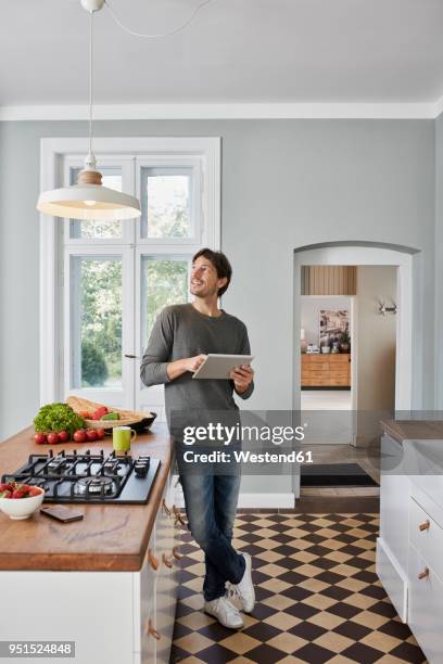 man using tablet in kitchen looking at ceiling lamp - smart kitchen fotografías e imágenes de stock