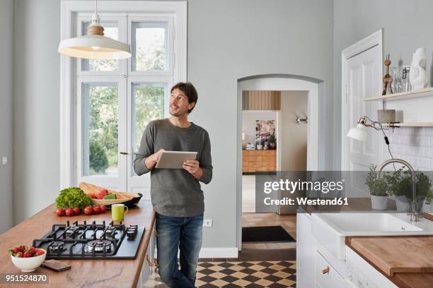 man using tablet in kitchen looking at ceiling lamp - internet of things stock-fotos und bilder