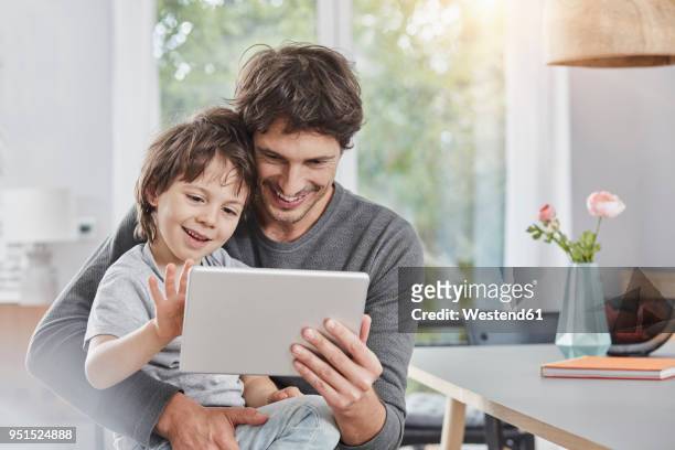 happy father and son using tablet at home together - family ipad stockfoto's en -beelden