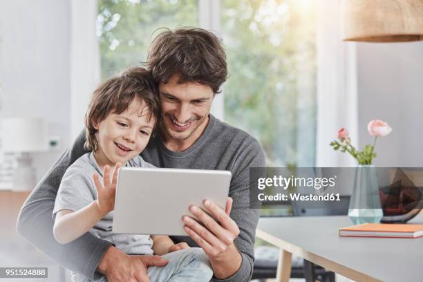 happy father and son using tablet at home together - family tablet stock pictures, royalty-free photos & images