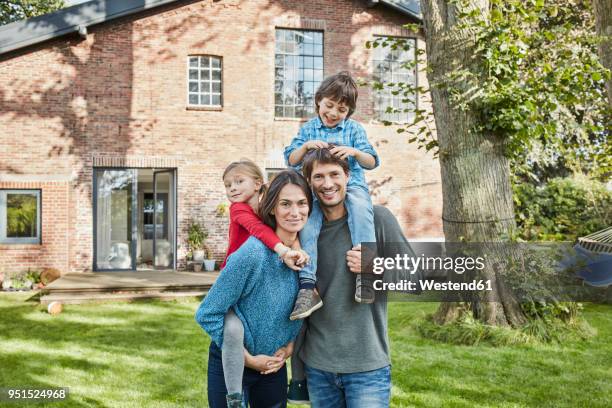 portrait of happy family in garden of their home - familie haus stock-fotos und bilder