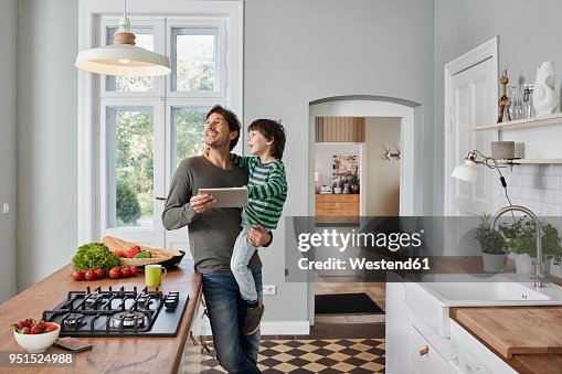 Father and son using tablet in kitchen looking at ceiling lamp Father and son using tablet in kitchen looking at ceiling lamp