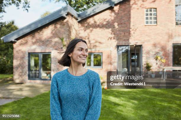 smiling woman in garden of her home - vor stock-fotos und bilder