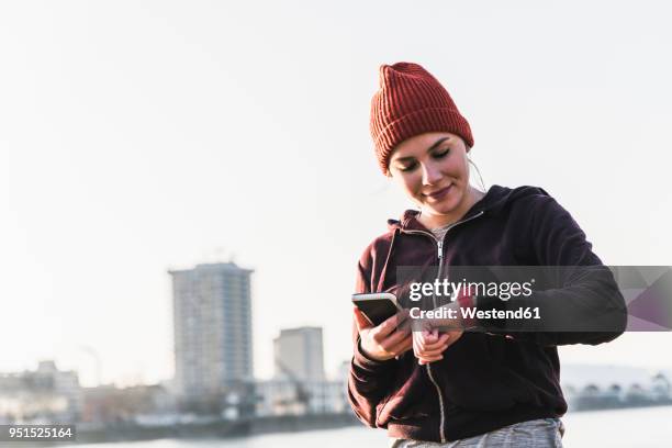 sportive young woman at the riverside in the city with smartphone and smartwatch - duration of training stock pictures, royalty-free photos & images
