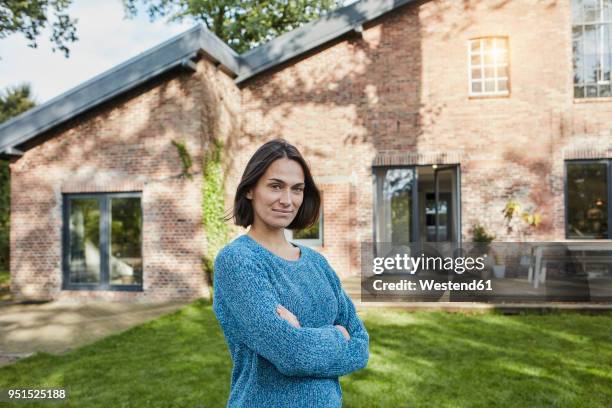 portrait of confident woman in garden of her home - stolz stock-fotos und bilder