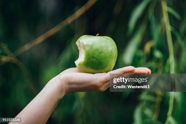 woman's hand holding bitten apple - morder imagens e fotografias de stock