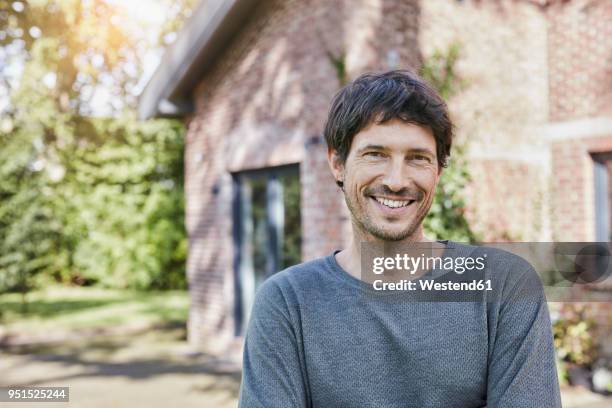 portrait of smiling man in front of his home - mann vor haus stock-fotos und bilder