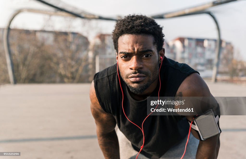 Portrait of young man on court with smartphone and earphones