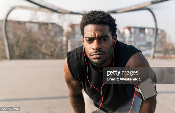 portrait of young man on court with smartphone and earphones - arm tattoos for black men fotografías e imágenes de stock