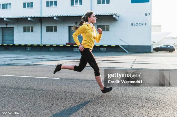 young woman running on a street - correr imagens e fotografias de stock