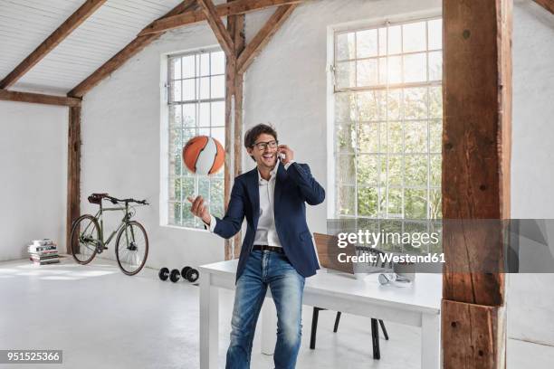 laughing businessman with basketball on cell phone in penthouse - ball on a table stockfoto's en -beelden