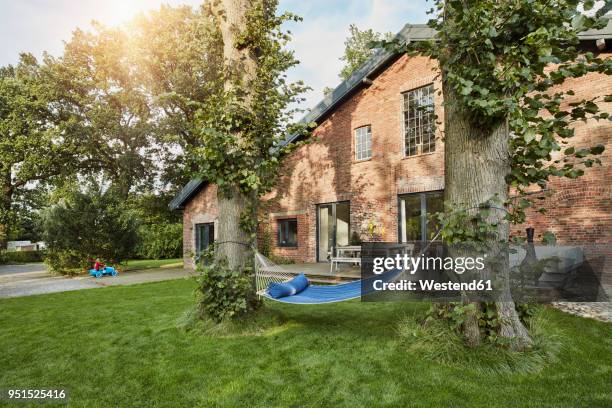 residential house with hammock in garden and girl playing in background - einfahrt stock-fotos und bilder