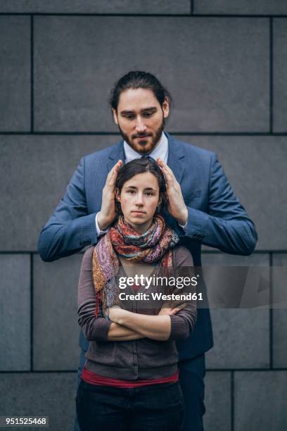 businessman covering woman's ears - small man and tall woman stock pictures, royalty-free photos & images