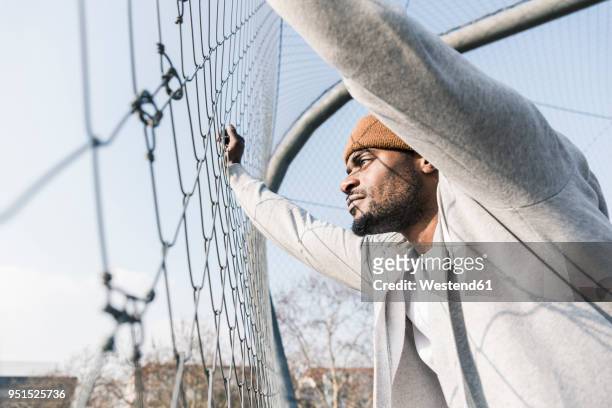 young man on court leaning against fence - sports field fence stock pictures, royalty-free photos & images