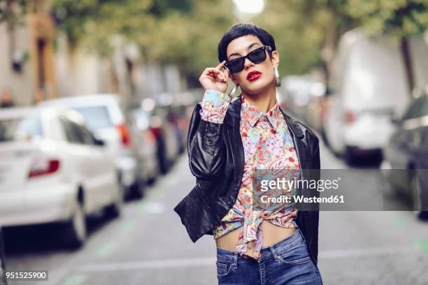 portrait of fashionable young woman wearing sunglasses and leather jacket - a la moda fotografías e imágenes de stock