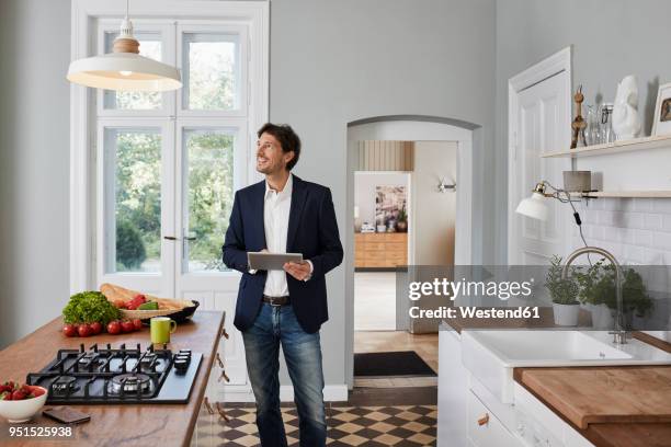 man using tablet in kitchen looking at ceiling lamp - blazer foto e immagini stock