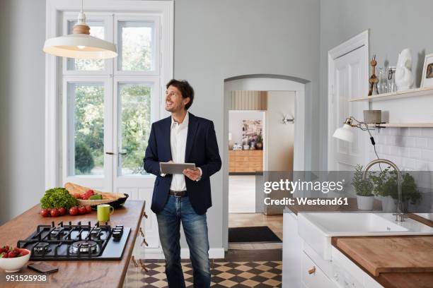 man using tablet in kitchen looking at ceiling lamp - one off stock pictures, royalty-free photos & images