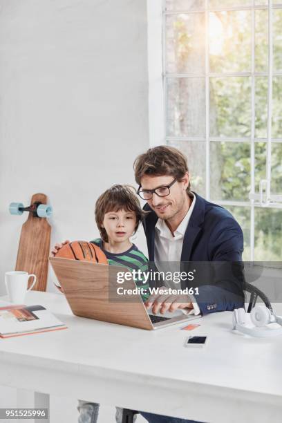 businessman and son using laptop at desk - kompatibilität stock-fotos und bilder