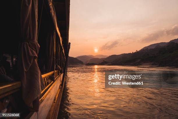 laos, mekong river, boat at sunset - laos imagens e fotografias de stock