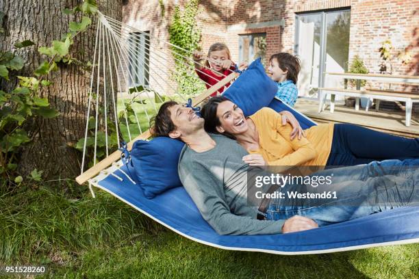 happy family playing in hammock in garden of their home - couple resting stock pictures, royalty-free photos & images