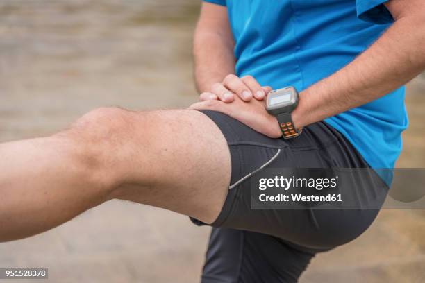 man stretching leg, wearing a smartwatch - hamstring stock pictures, royalty-free photos & images