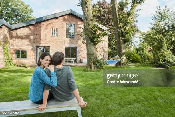 smiling affectionate couple sitting in garden of their home - gartenhaus stock-fotos und bilder