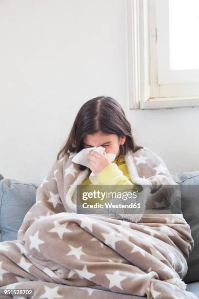 girl having a cold sitting on the couch at home blowing nose - sneeze stock pictures, royalty-free photos & images