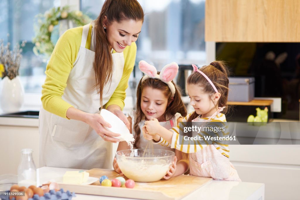 Mother and daughters baking Easter cookies in kitchen together