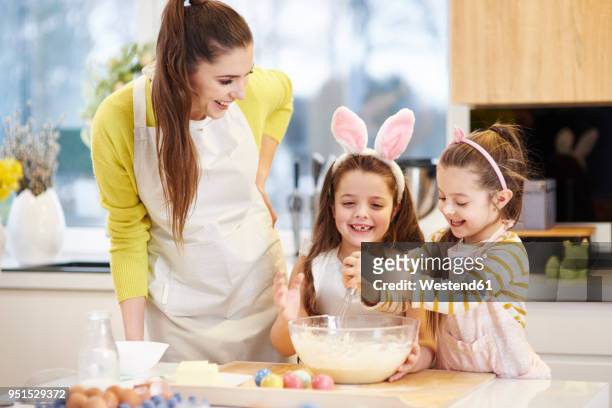 happy mother and daughters baking easter cookies in kitchen together - famille pâques photos et images de collection