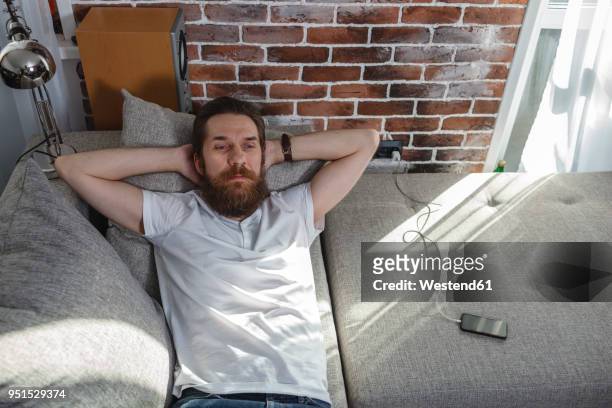 portrait of bearded man relaxing on the couch at home - mur maison ombres photos et images de collection