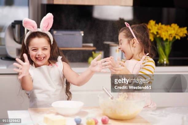 two playful sisters having fun baking easter cookies in kitchen together - funny easter eggs 個照片及圖片檔