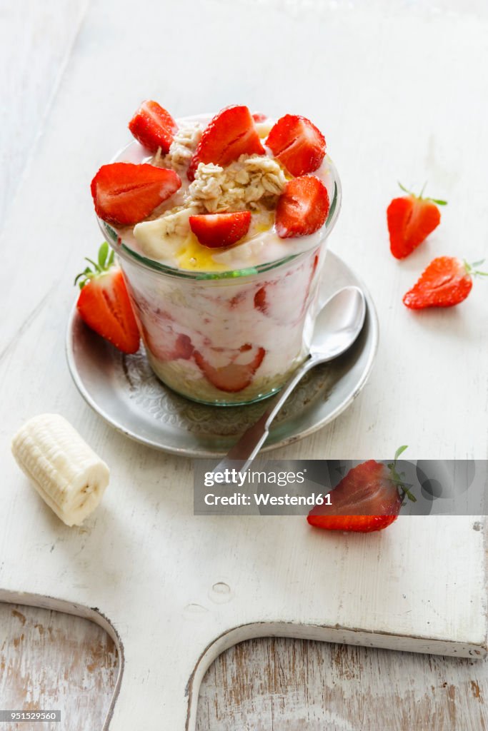 Strawberry banana parfait with oat flakes and yogurt in glass