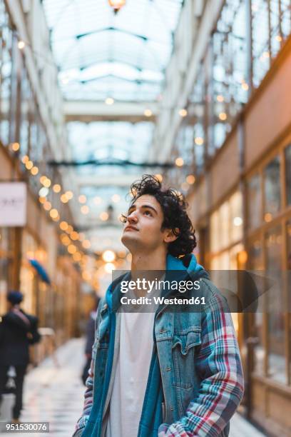 portrait of smiling young man in shopping centre - paris millenials stock-fotos und bilder