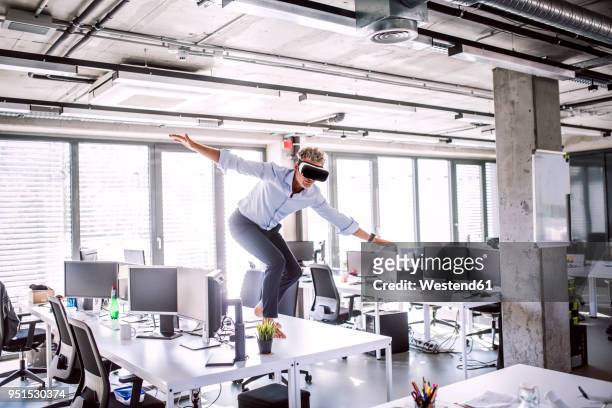 barefoot mature businessman on desk in office wearing vr glasses - person surrounded by computer screens stock pictures, royalty-free photos & images