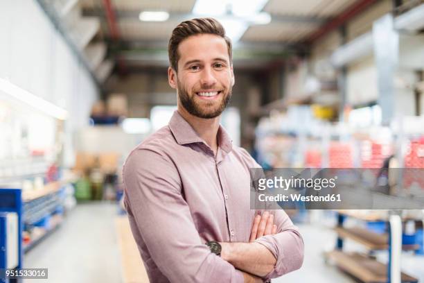 smiling businessman in production hall - solo un uomo giovane foto e immagini stock