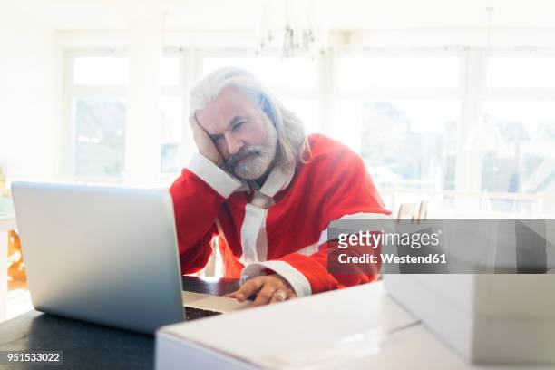 frustrated santa using laptop at home - job search stress stock pictures, royalty-free photos & images