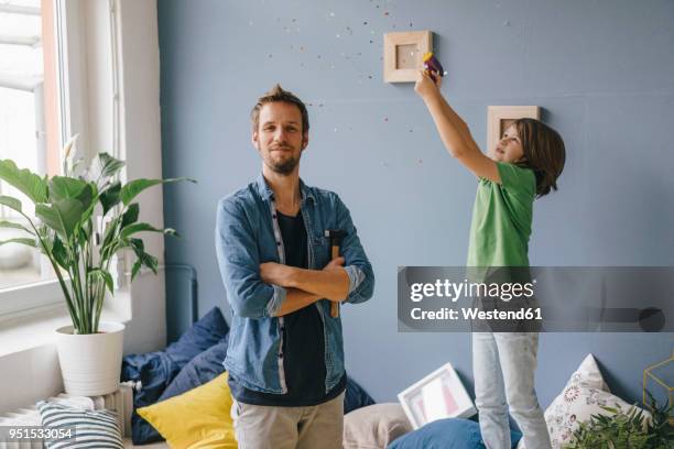 son blowing confetti over proud father holding hammer at home - european best pictures of the day may 7 2013 stockfoto's en -beelden