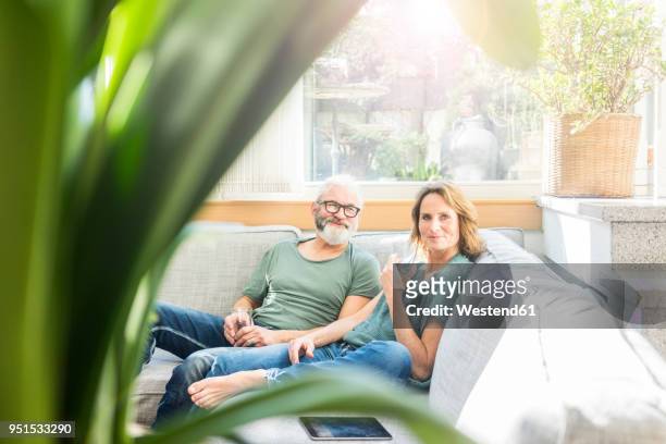 mature couple relaxing on couch at home - wasser trinken zu hause stock-fotos und bilder